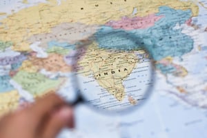 Eine Lupe, die auf Indien gerichtet ist und die Details des Landes deutlich hervorhebt. Die umliegenden Regionen auf der Karte sind bewusst unscharf dargestellt, um den zentralen Fokus zu betonen.