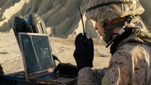 Military member using walkie and computer