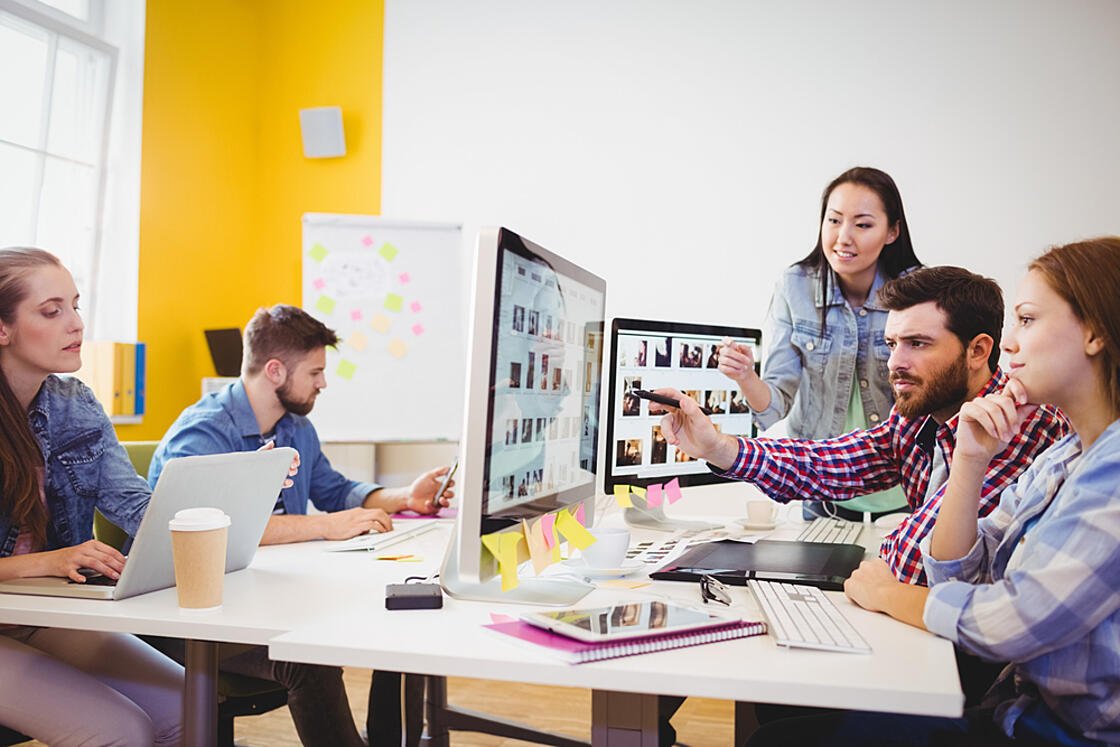 Businessman showing computer screen to coworkers in creative office - 副本