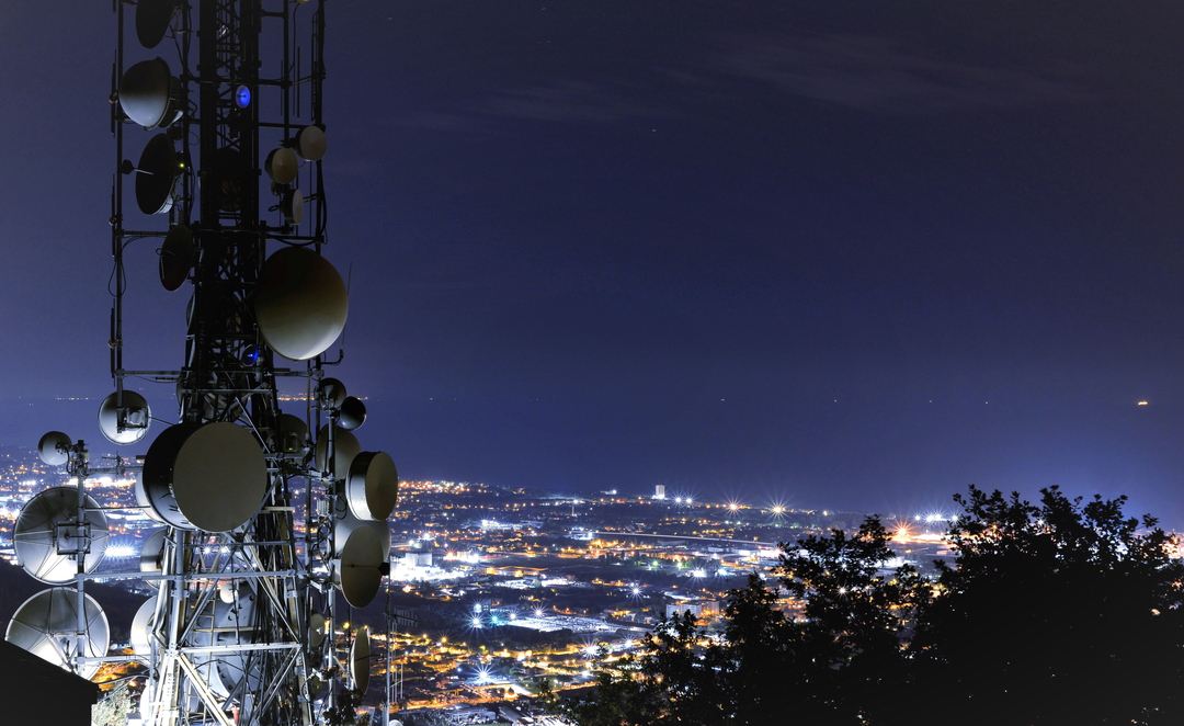 Telecommunications tower, antenna and satellite dish and city at night as background - Radio, 5G, wireless